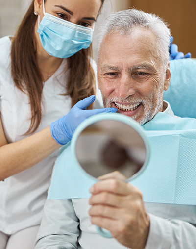 Dental Implants, image of a bearded older man smiling at the dentist after getting his dental implants