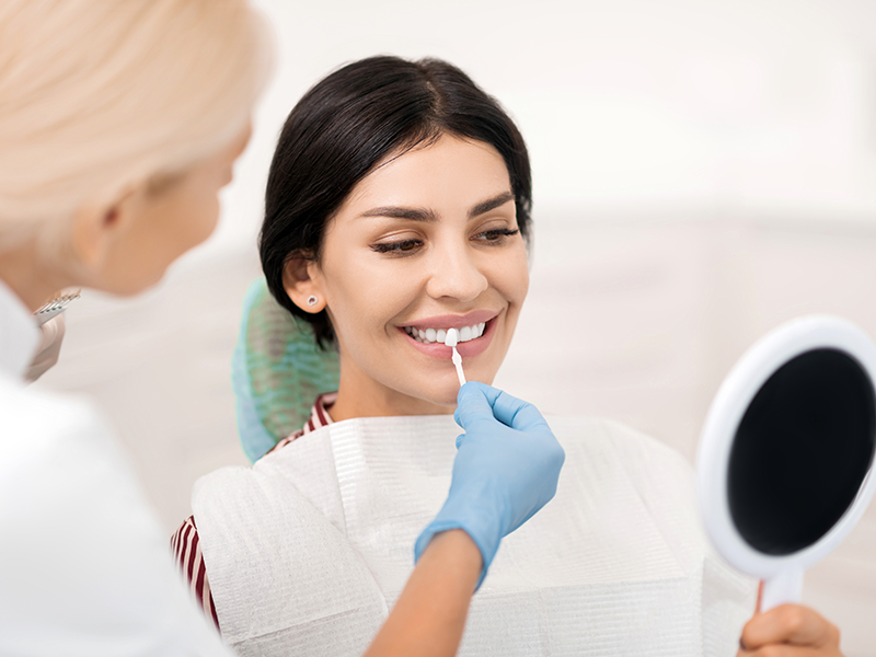 dental services-Teeth Whitening, image of a Woman trying on teeth whitening sample at dentists