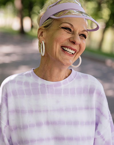Restorative Dentistry, image of an older woman smiling while walking outside.