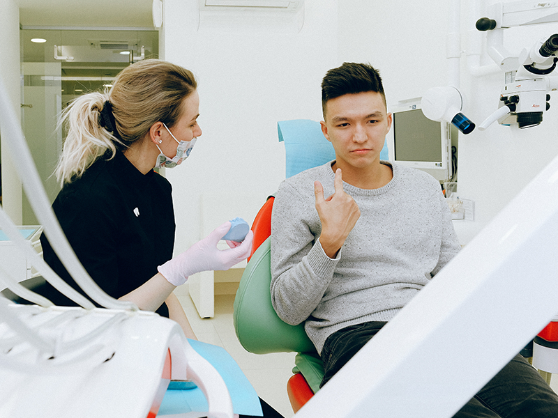 dental services, general dentistry, image of a young man pointing to his mouth during a dental visit.
